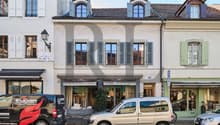 4 story building, white walls, gray shutters, storefronts on first floor