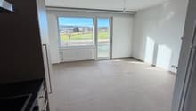 tiled floor, large glass window, white walls, ceiling lamp, kitchen area with black countertop