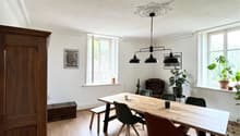 long dining table, white wooden bench, modern chairs, vintage cabinet, white walls, picture frames, ceiling lamp, large windows, wooden floor