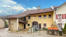 two-story house, yellow facade, tiled roof, wooden balcony, chimneys, fenced garden, driveway, green gates