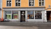 A building with orange walls, four windows, and a glass door with the Nespresso logo. A bicycle is parked in front of the building on the sidewalk.