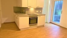 modern kitchen with white cabinetry, wooden floors, built-in oven, stainless steel sink, tiled countertop