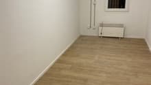 Empty room with wooden floors, white walls, an exit door with a glass panel, and an electrical outlet.