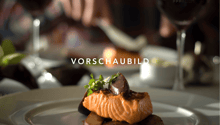 A plate of salmon with vegetables and a garnish of herbs