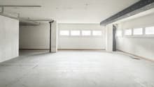 Empty room with a concrete floor, white walls, a pipe on the wall, and multiple windows