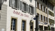 white facade, multiple windows with shutters, sign reading Balthof zum Raben
