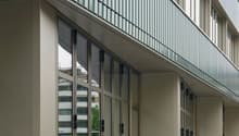 modern office building, glass facade, multiple floors, balcony with metal railings, wide entrance