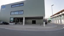 modern commercial building, steel and concrete, green facade, large glass windows, main entrance with glass doors, signage