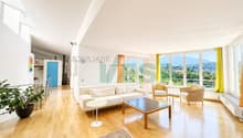 una stanza con un'ampia finestra, un pavimento in legno, un divano bianco e un tavolo in legno / a room with a large window, a wooden floor, a white couch, and a wooden table