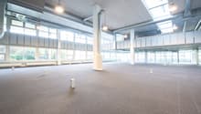 Wide open space, large windows, hanging lamps, central column, balcony with railings, metal ducts on ceiling