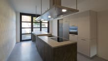 modern kitchen with island, two sinks, induction cooktop, oven, extractor hood, white cabinets, tiled floor