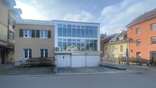 3-story building with a garage in front and glass windows.
