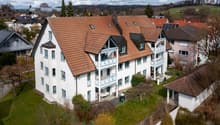 3-story house, brown roof, white walls, blue trim, multiple balconies, multiple windows, garden, solar panels