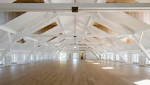 large open space, wooden floor, white walls, white beams, windows, wooden ceiling
