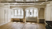 bare room with hardwood floors, white walls, arched windows, benches, radiator