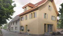 Two-story yellow house, brown roof, glass doors and windows, two shrubs, three cars parked
