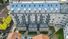 modern residential building, multiple balconies, large glass windows, landscaped area