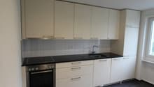 modern kitchen with white cabinets, black countertops, stainless steel oven, sink with faucet, electrical outlets