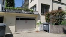 white building with balcony, glass door, signboard, trash bin