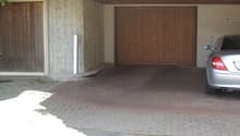 Garage space with a wooden door, brick floor, and parked car.