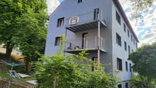 3 story house, gray exterior, metal balconies, surrounded by trees