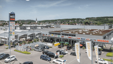 Modern building with parking area, sign indicating Migros store