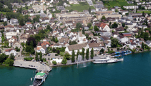 View of the town with many houses, buildings, a fountain, and a lake with boats