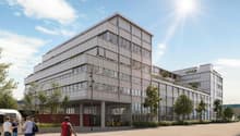 An artist's impression of a modern, multi-story building with raised ground floor, surrounded by trees and parked vehicles.