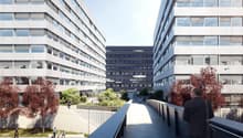 modern office building with glass facades, landscaped garden area, pathways connecting buildings, overhead lighting fixtures