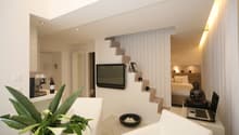 Minimalist interior, white walls, modern design, bed in bedroom, television, small black bowl, laptop, plant in a white pot
