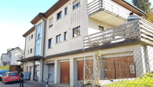 3-story apartment building with a balcony, garage, and fenced outdoor area