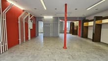 empty room, gray floor, red walls, red pillar, fluorescent ceiling lights, two doors, metal racks on the wall