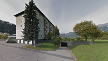 2-story apartment building with garage, surrounded by trees, on a hill