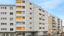 modern white high-rise building, yellow shutters, commercial spaces on the ground floor, street light