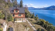 2 story house, red brick, green windows, solar panels, located on a hill, with a sea view