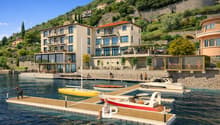 Building with multiple floors and terraces overlooking water, boats docked in front