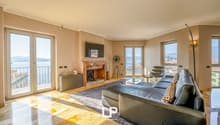 Spacious living room with large windows, balcony, fireplace, leather sofa, and modern decor