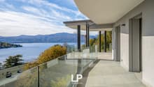 building exterior, glass railings, lake view, terrace, mountains in background