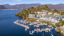 Marina with many boats docked, surrounded by mountains and a lake, multiple residential buildings