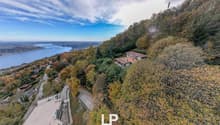 House on hillside, view of lake and city, trees, dirt road, another house in background