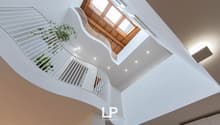 curved staircase, white railings, wooden ceiling, skylights, plants