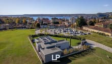 Modern building, solar panels on the roof, landscaped surroundings, parking lot, lush green fields