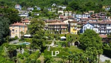 Cluster of houses in a hillside community, multiple pools, lush greenery, trees, distant mountain range