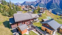Group of detached chalets, wooden architecture, mountain view, surrounding greenery