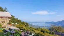 astonishing views of the mountains and the sea, beautiful landscaping, two white chairs, and potted plants