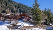 wooden chalet, red shutters, balcony, snow-covered ground, mountain view