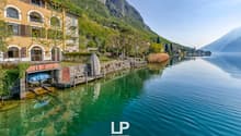 House on the lake, with a dock, surrounded by mountains and greenery