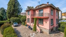 2 story house, pink exterior, brick ground floor, balcony, parking place, garden, trees