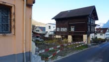 brown wooden house, gable roof, multiple windows, mountains in the background
