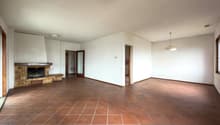 large empty room, brick fireplace, terracotta tiles, white walls, ceiling lights